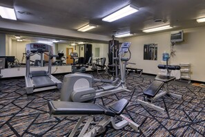 A gym with treadmills, elliptical machines, and weight benches.