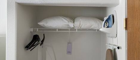 A white closet with a hanging rack, a pair of black shoes, and a 'Do Not Disturb' sign.