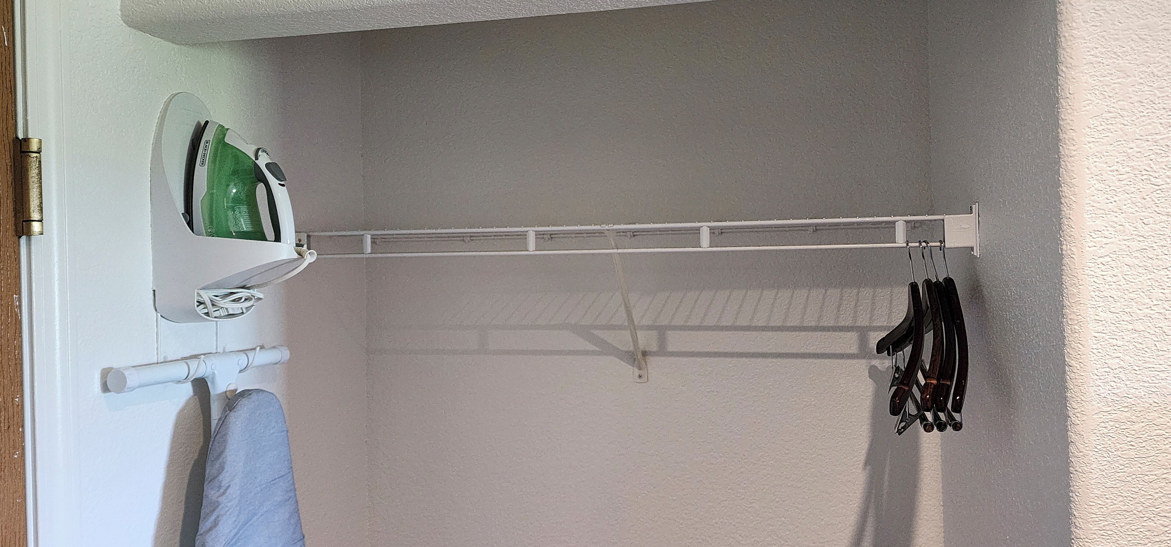 A bathroom with a towel rack, a green iron, and a rack holding black hair tools.