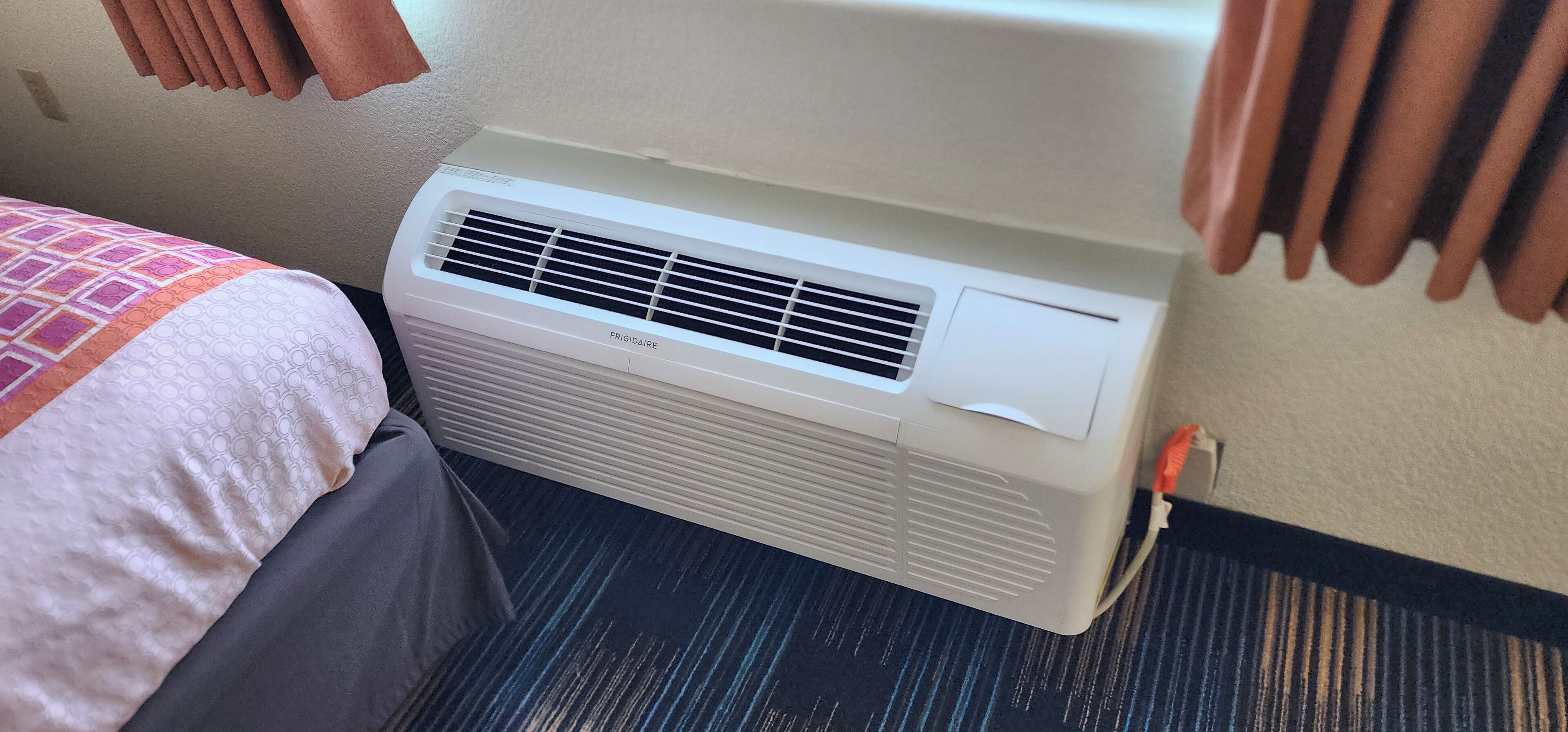 Un equipo de aire acondicionado blanco instalado en una pared dentro de una habitación de hotel.