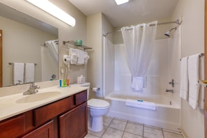 A bathroom with a sink, mirror, toilet, and bathtub.