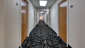 Un pasillo largo y estrecho con pisos alfombrados y puertas de madera a ambos lados.