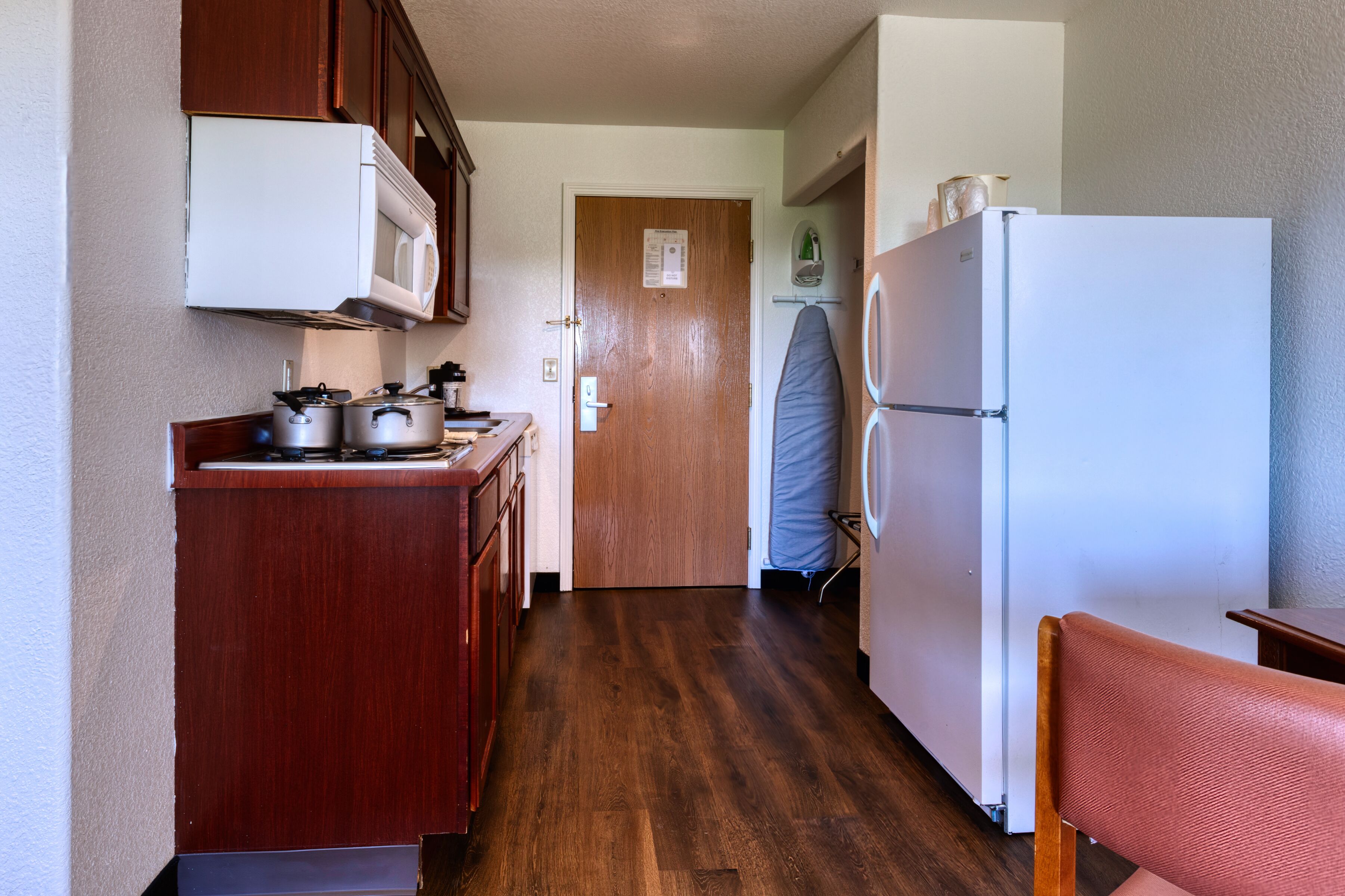 Una cocina compacta con armarios de madera, un refrigerador blanco y un microondas.