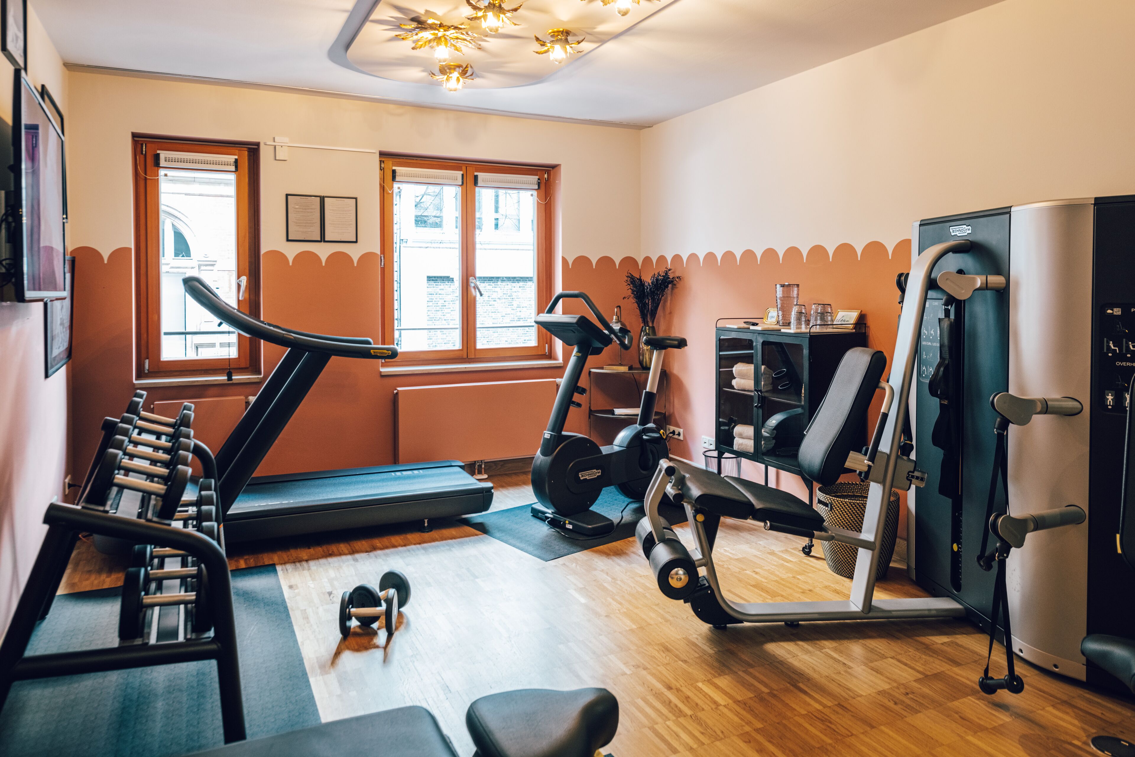 Ein Fitnessraum mit Laufband, Crosstrainer und Kraftgeräten.