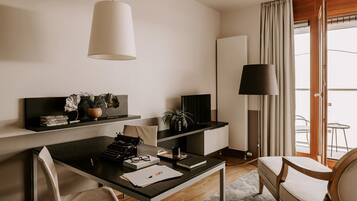 Una habitación de hotel moderna con escritorio, silla y un ventanal con cortinas.