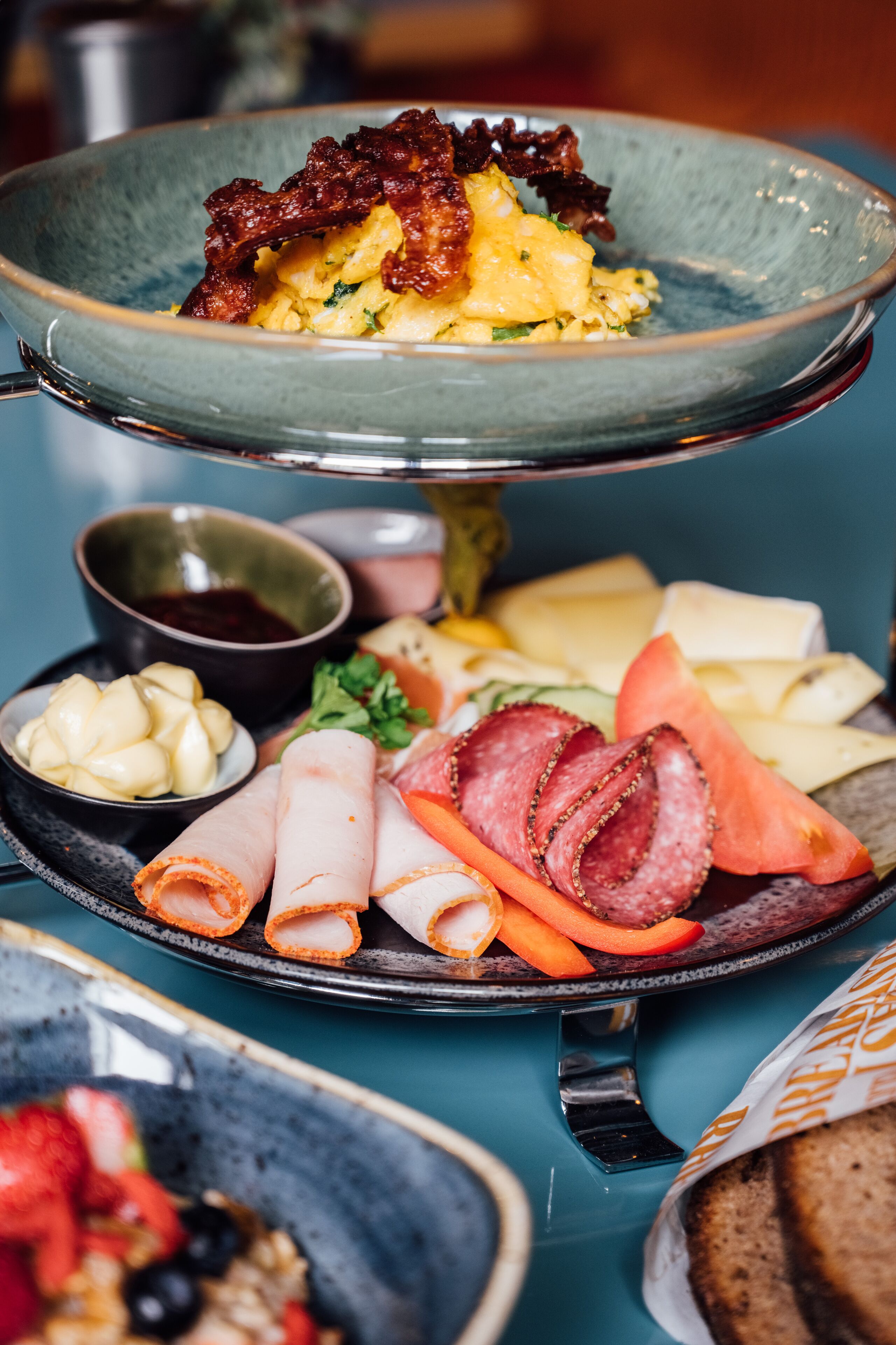 A multi-tiered serving dish with various food items including eggs, bacon, cheese, and vegetables.