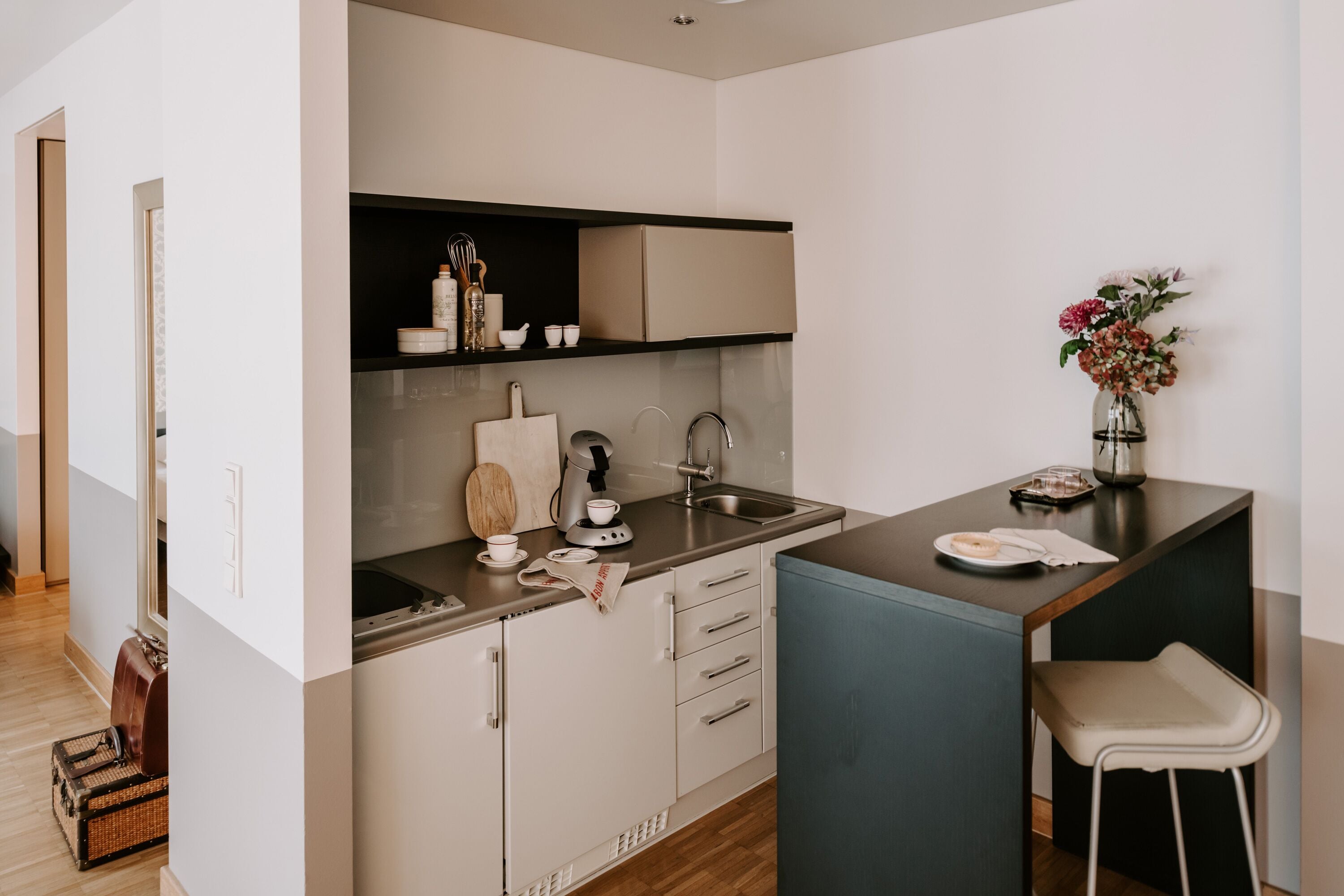 Une cuisine compacte comprenant un évier, un plan de travail et un petit coin repas avec une chaise.