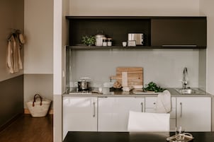 A modern kitchen with white cabinets, a wooden countertop, a sink, and a dining area with a table and chairs.