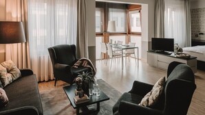 Moderni hotellihuone, jossa on oleskelualue, ruokailutila ja sänky.