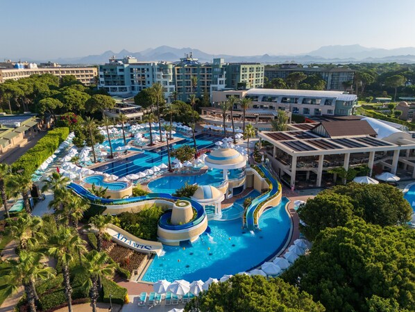 A resort with multiple swimming pools, palm trees, and a mountainous backdrop. - Limak Atlantis De Luxe Hotel & Resort - All Inclusive (Serik)