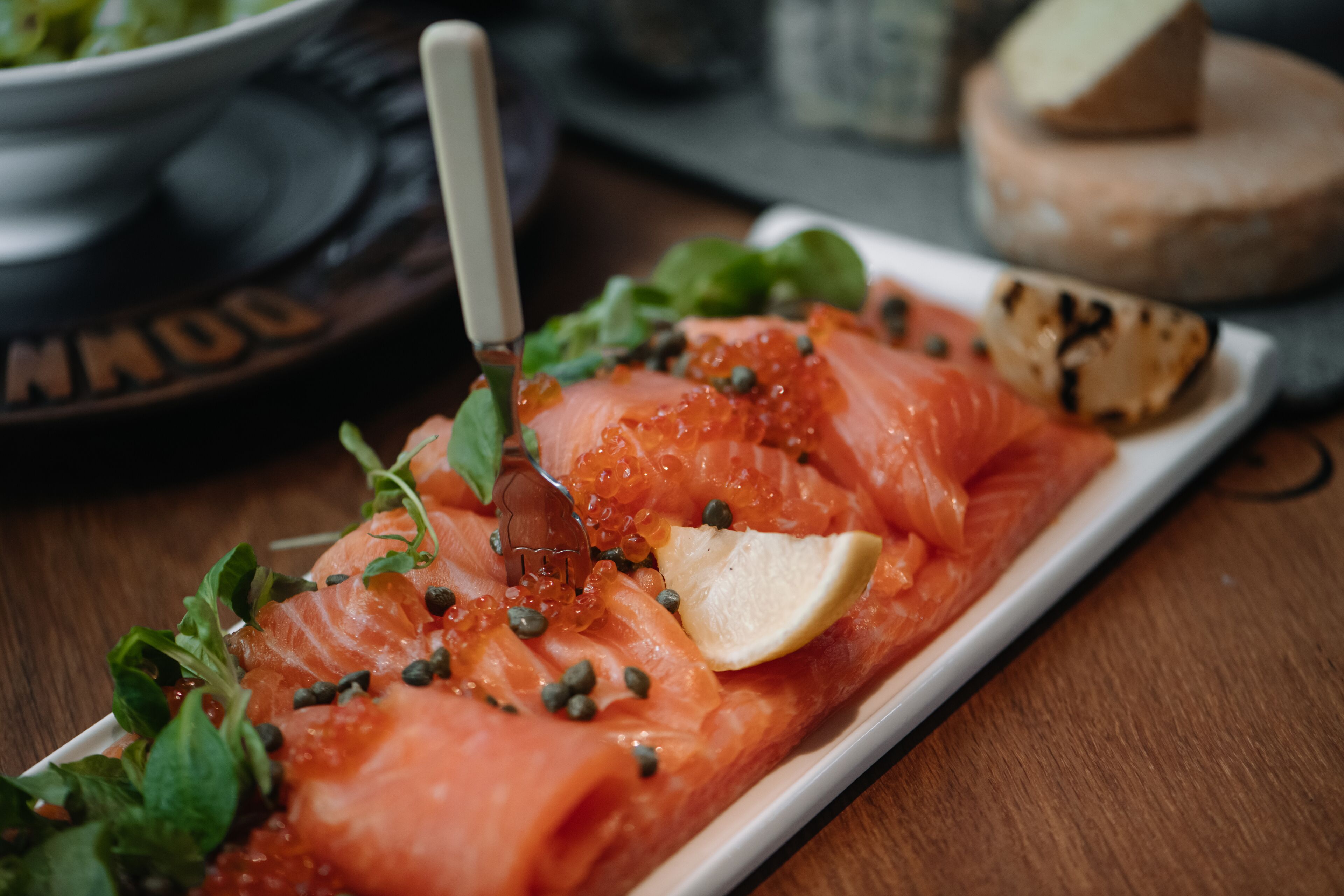A plate of smoked salmon garnished with capers and a lemon wedge.