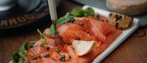 A plate of smoked salmon garnished with capers and a lemon wedge.