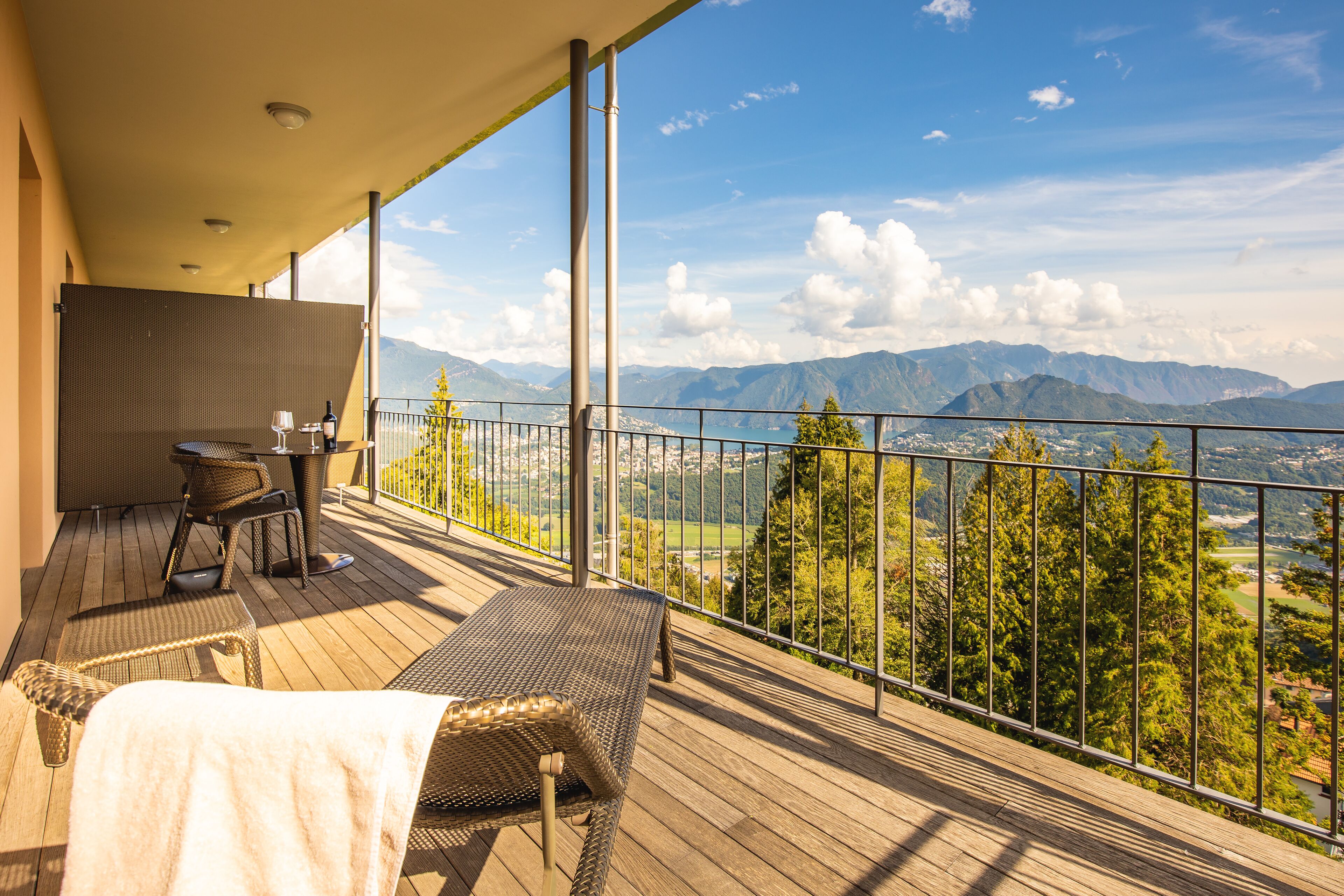 Un balcon agrémenté de meubles en osier, d’une table et d’une bouteille de vin.