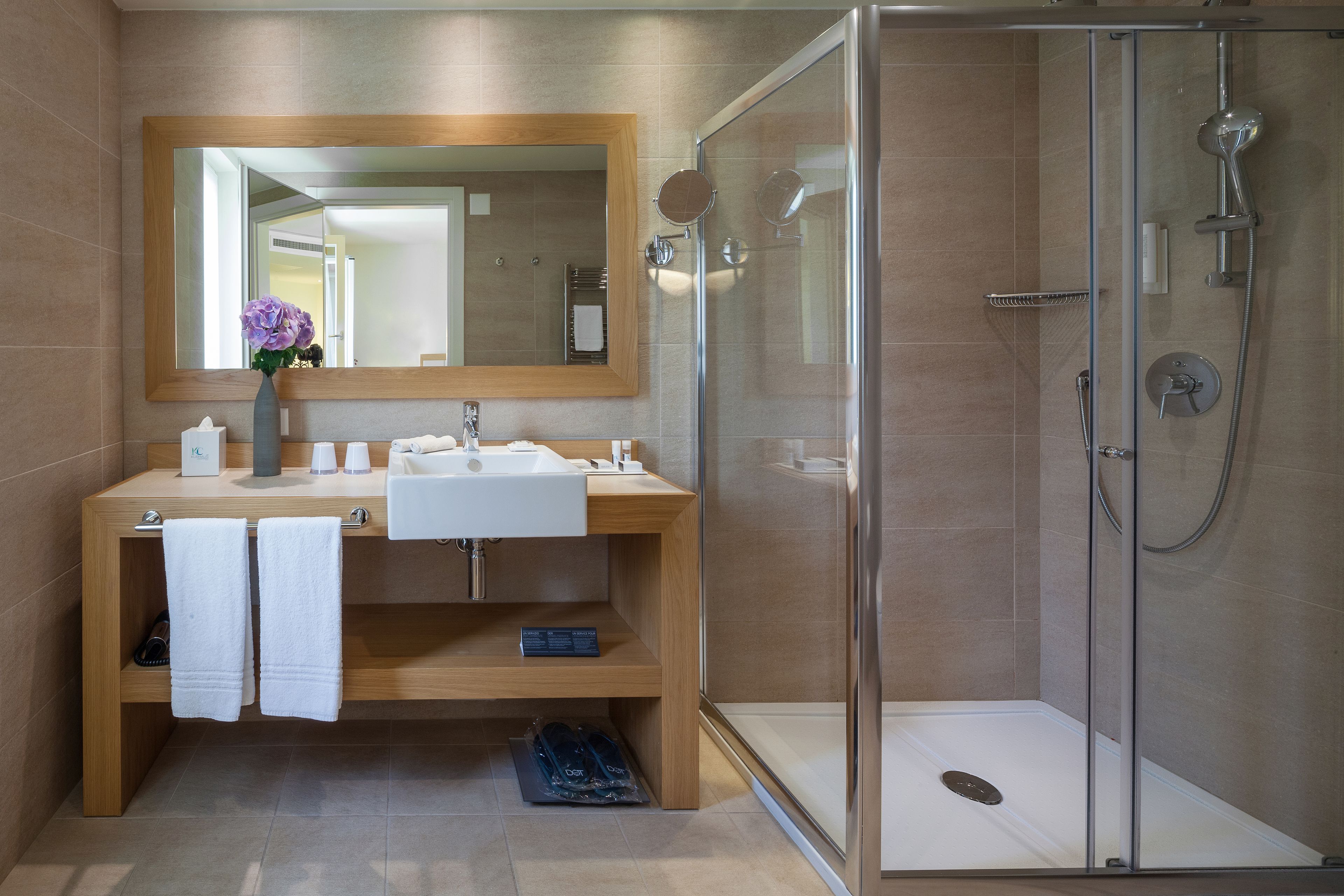 Ein modernes Badezimmer mit Duschkabine, Holzkosmetikschrank mit Waschbecken und großem Spiegel.