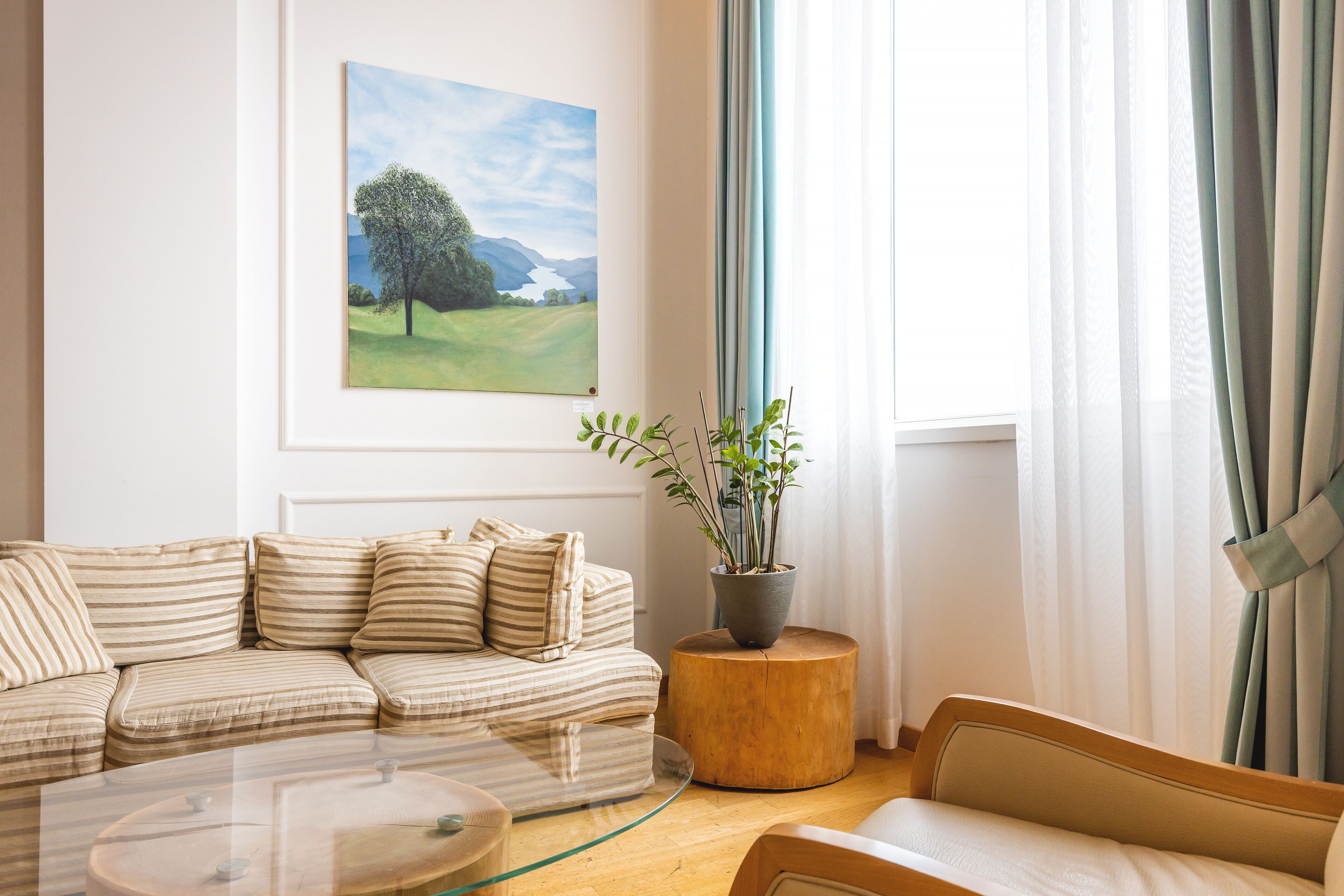 Een woonkamer met een bank, een bijzettafeltje en een schilderij aan de muur.