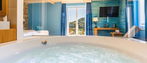 Un baño moderno con una bañera grande, un banco de madera y vistas al exterior.