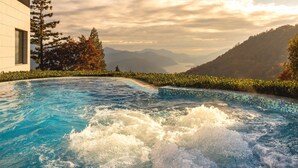 A hot tub with a view of mountains and a body of water.