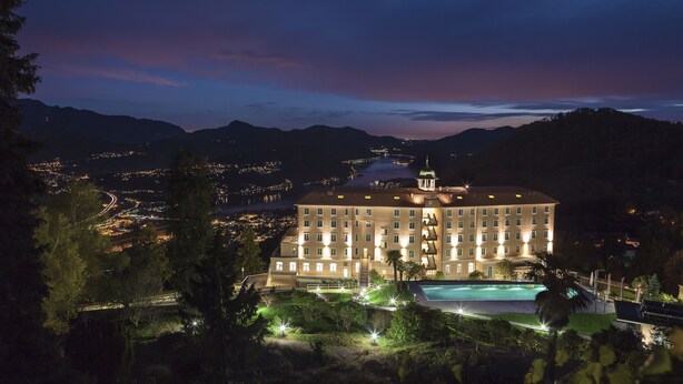 A large hotel with multiple floors, a swimming pool, and a view of the surrounding landscape.