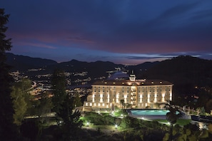 A large hotel with multiple floors, a swimming pool, and a view of the surrounding landscape. - Kurhaus Cademario Hotel & SPA (Cademario)