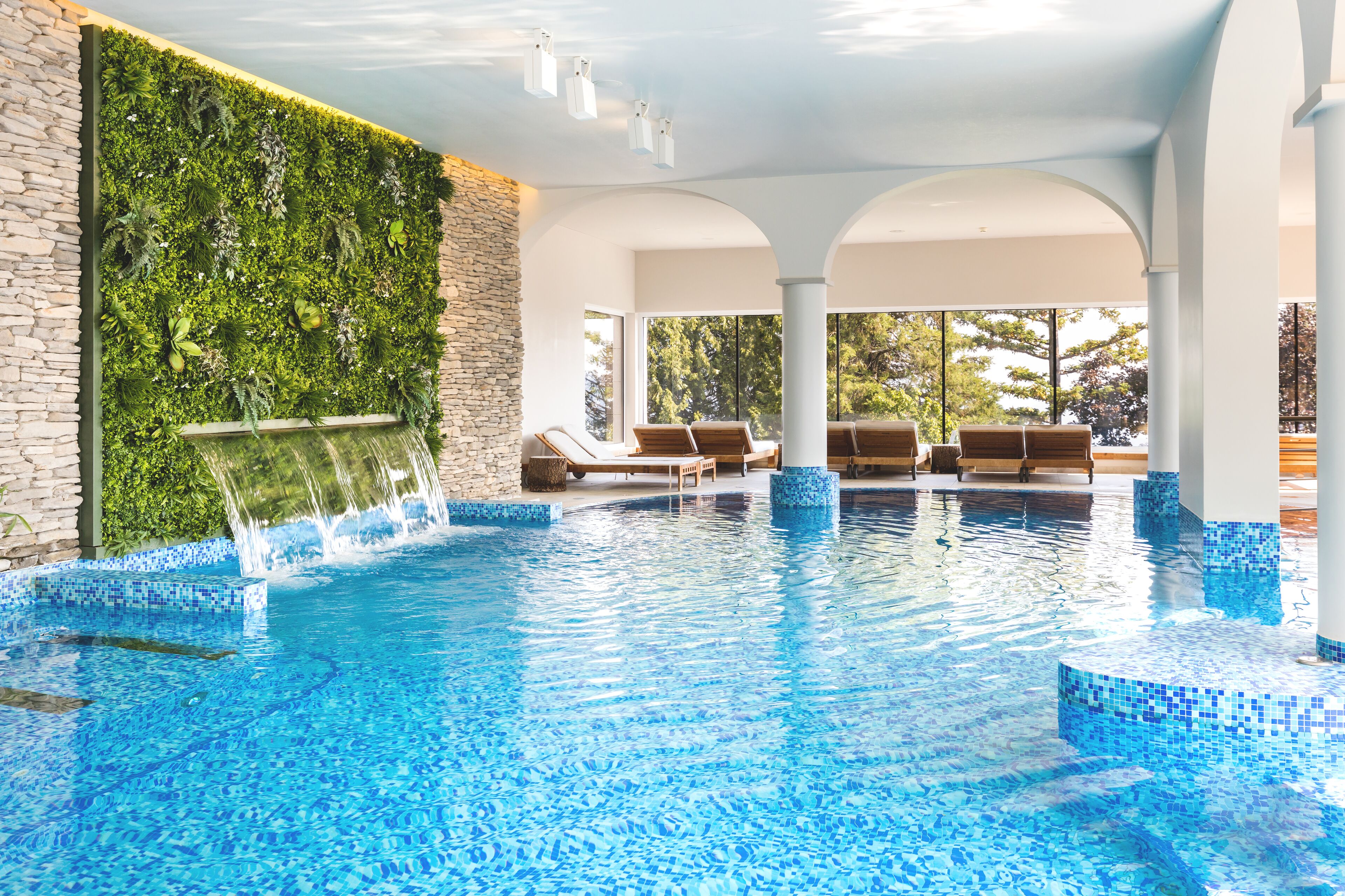 Alberca techada, alberca al aire libre y sombrillas en la alberca