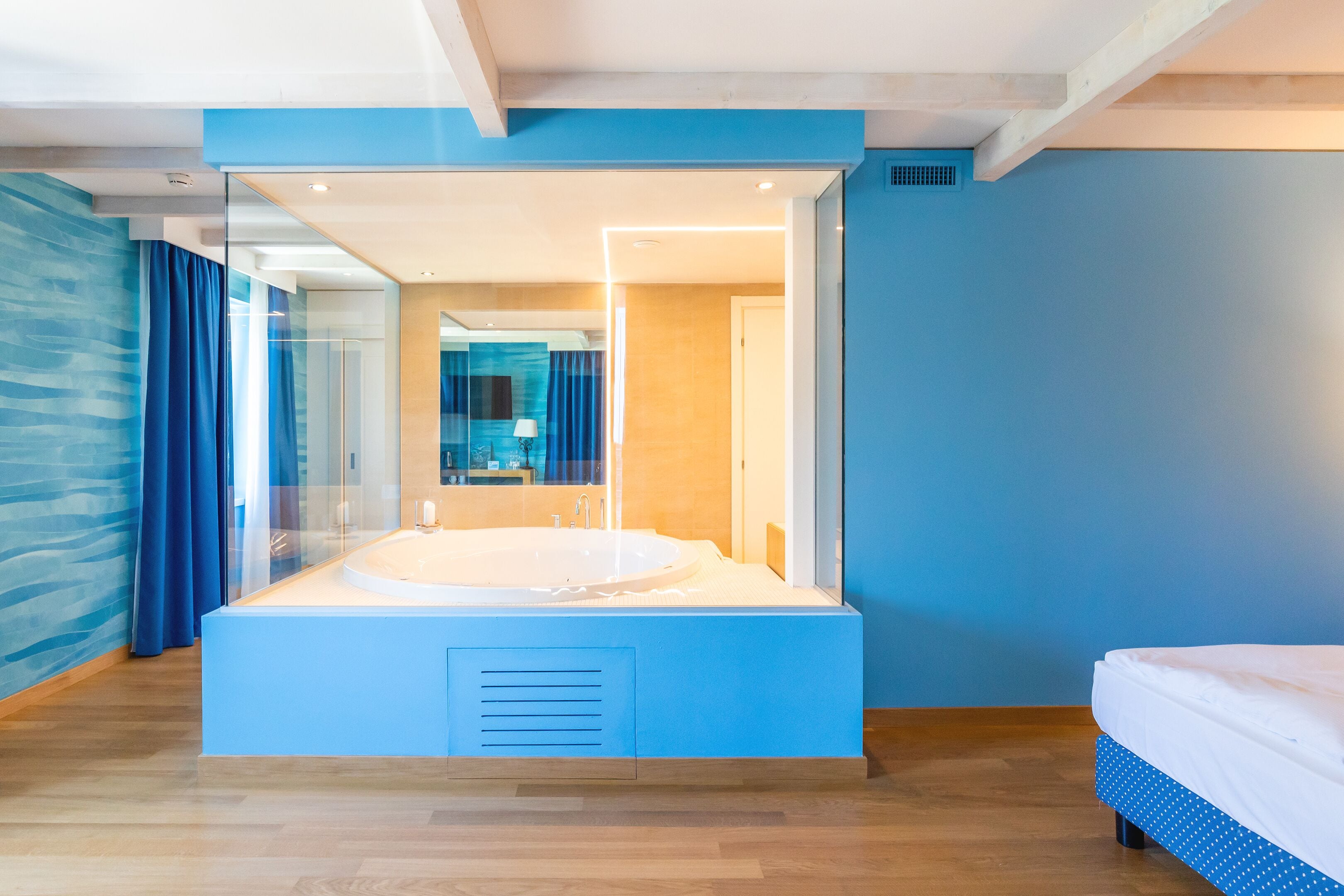 A modern bathroom with a large bathtub, a glass shower enclosure, and a wooden floor.
