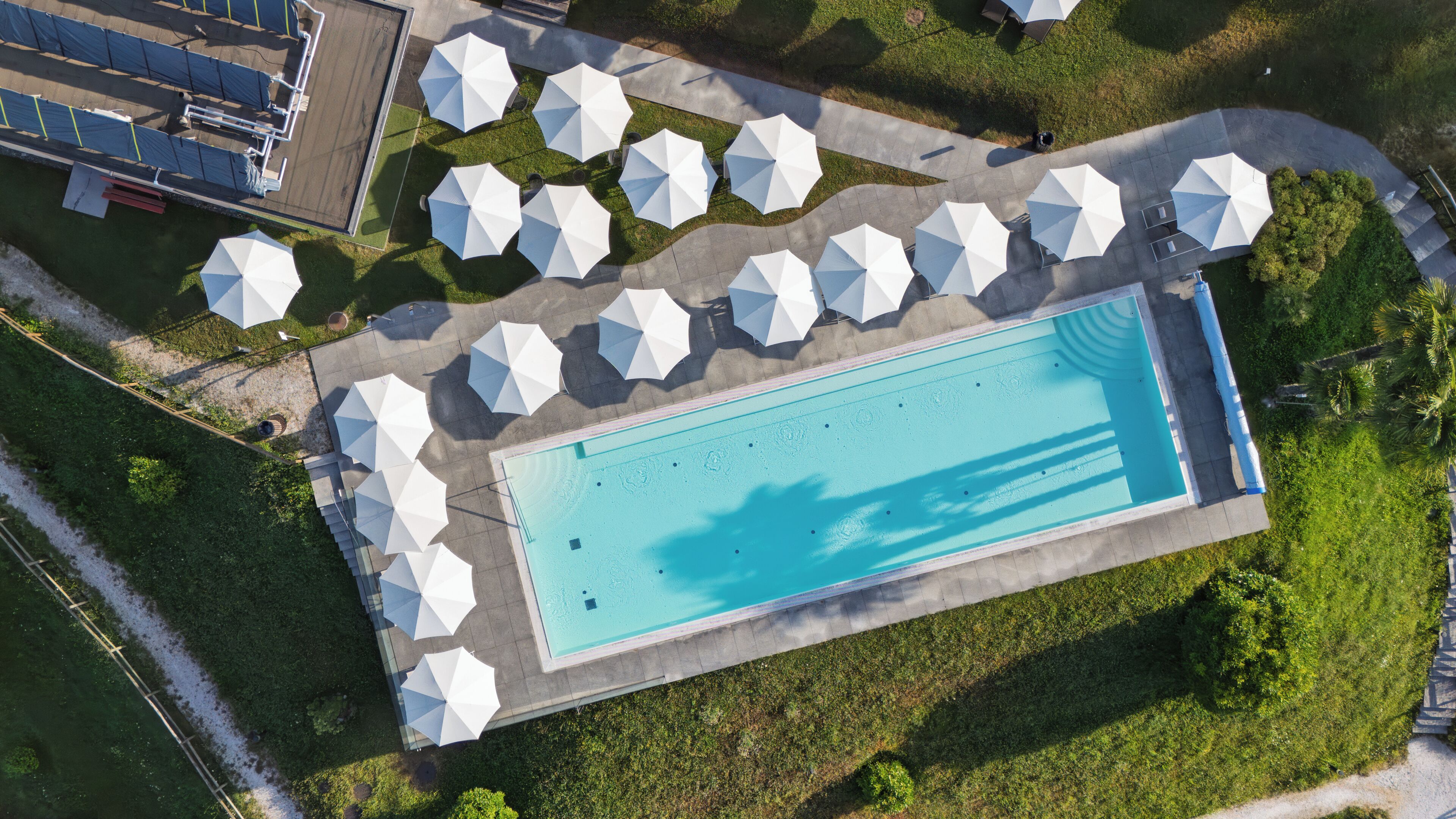An aerial view of a swimming pool with surrounding umbrellas and a clear blue water surface.