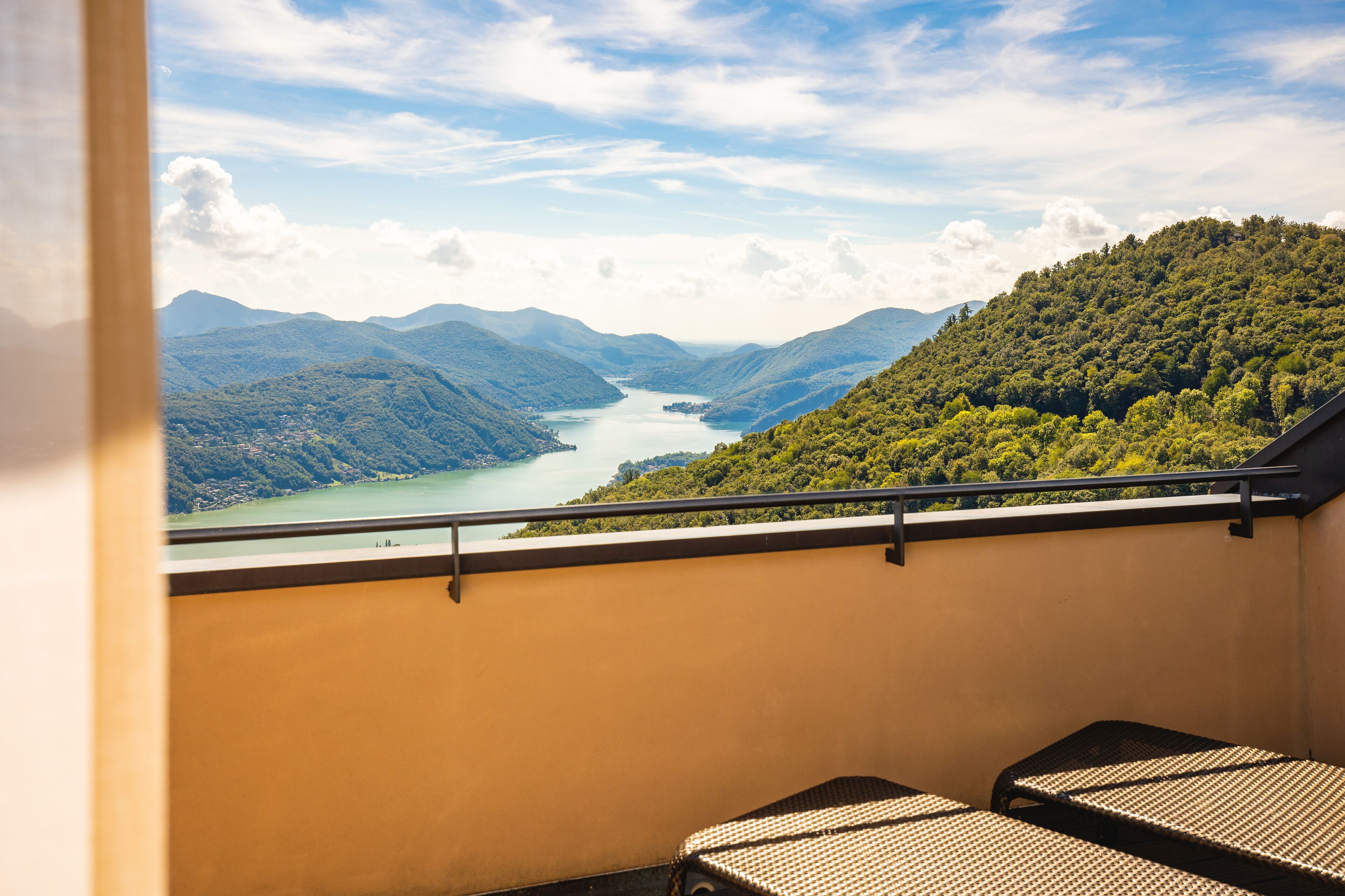 A balcony with a view of a lake surrounded by mountains.