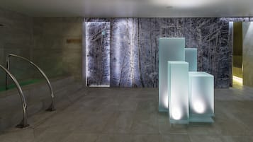 Un vestíbulo moderno con un mural grande en la pared, una escalera y varios paneles iluminados.