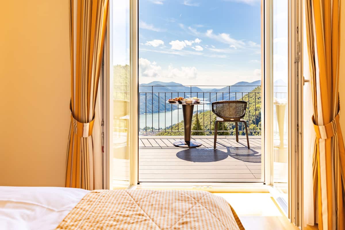 A balcony with a table and chair, overlooking a scenic mountain view.