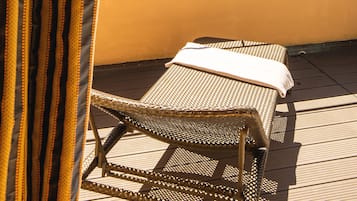 Un balcon avec un fauteuil en osier et une vue sur un lac entouré de montagnes.