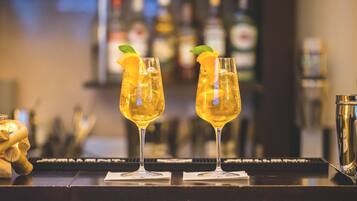 Deux verres d’une boisson jaune, décorés de tranches d’orange et de feuilles de menthe, sont posés sur le comptoir d’un bar.