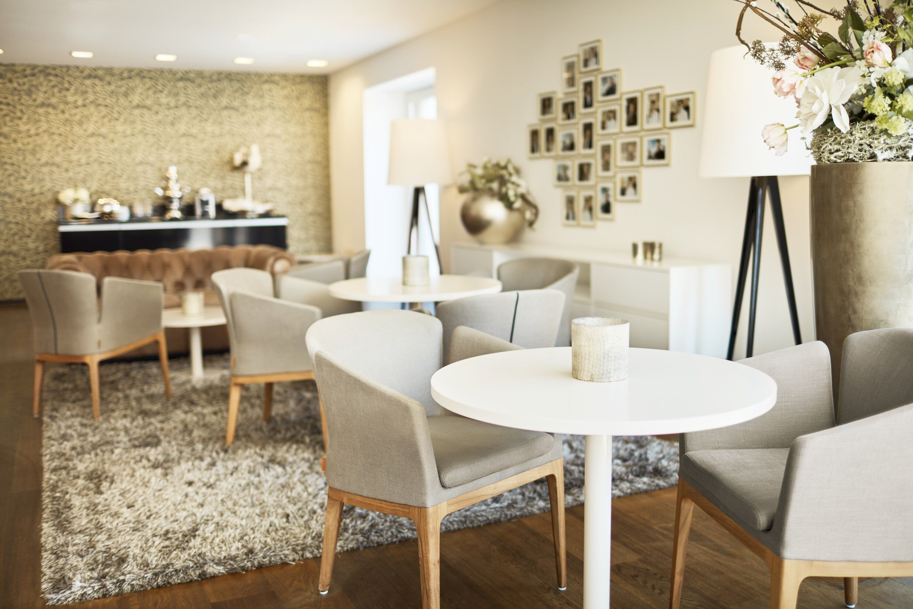 Un vestíbulo de hotel moderno con una mesa redonda y sillas, una zona de bar y una pared decorada con fotos enmarcadas.