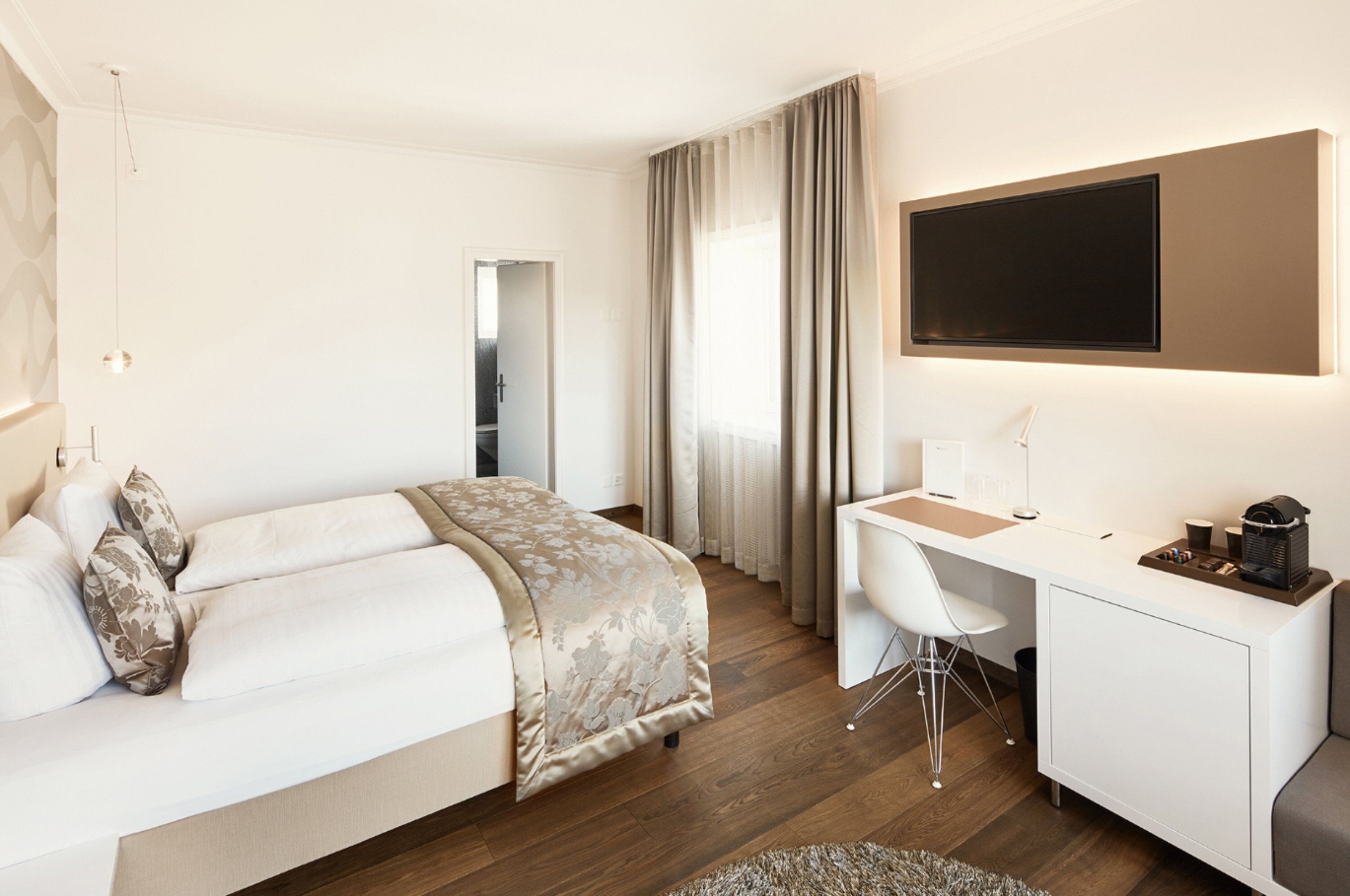 Una camera d'albergo moderna con un letto, una scrivania e una TV.