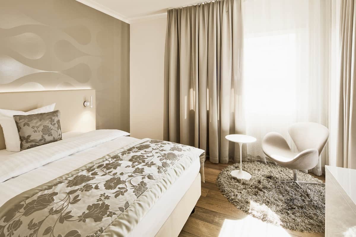 A modern bedroom with a large bed, a small round table, and a chair.