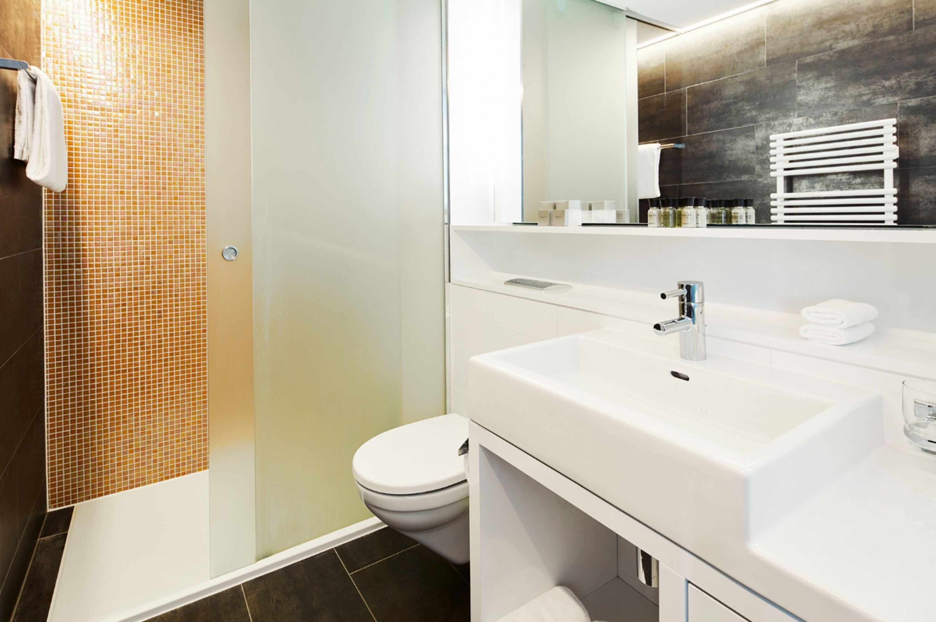 Ein modernes Badezimmer mit Duschkabine aus Glas, einem weißen Waschbecken und einer Toilette.