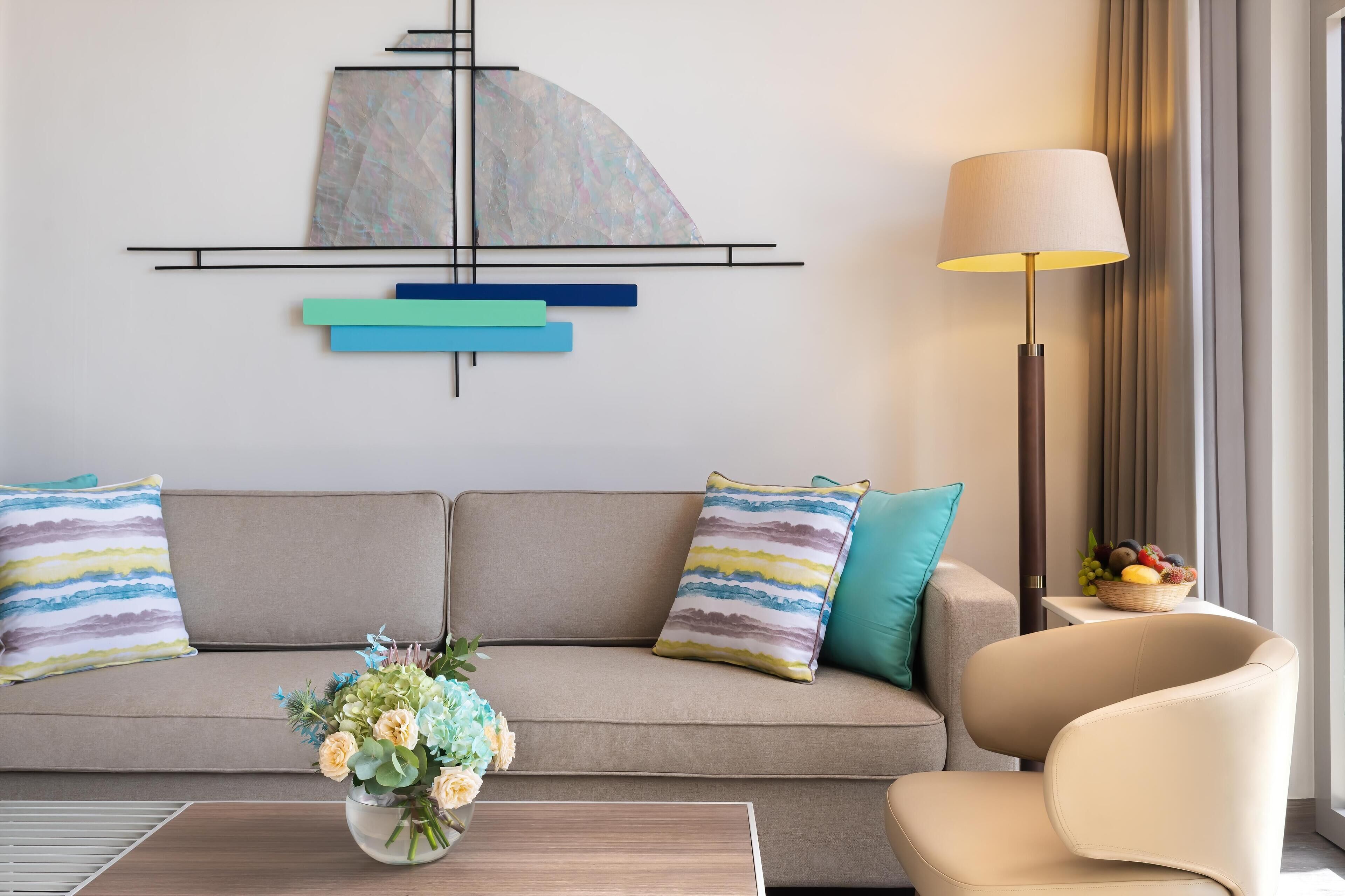 Un salon moderne avec un canapé, une table basse, une lampe et une œuvre d’art murale.