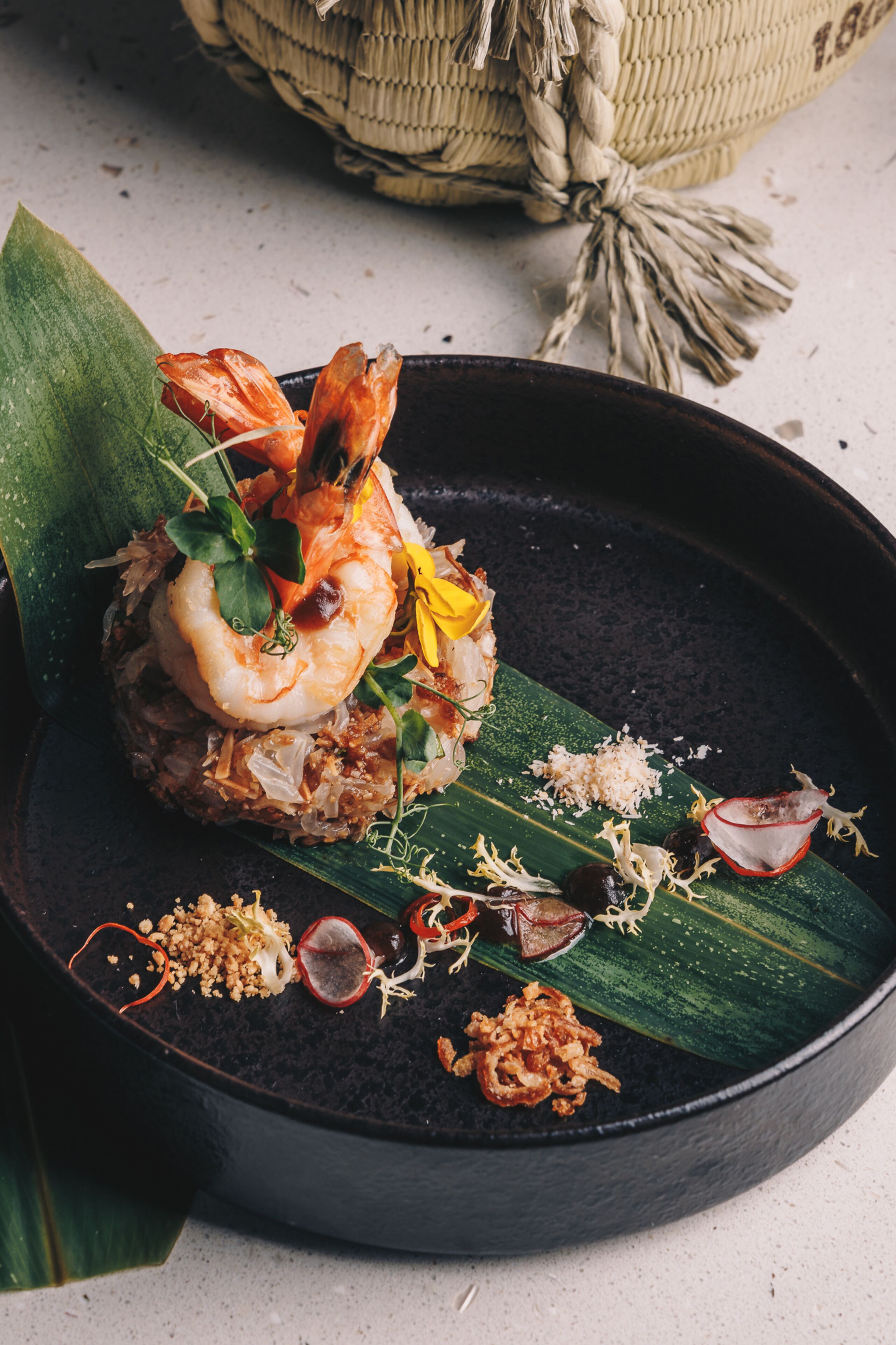 A dish with shrimp and vegetables on a dark plate.