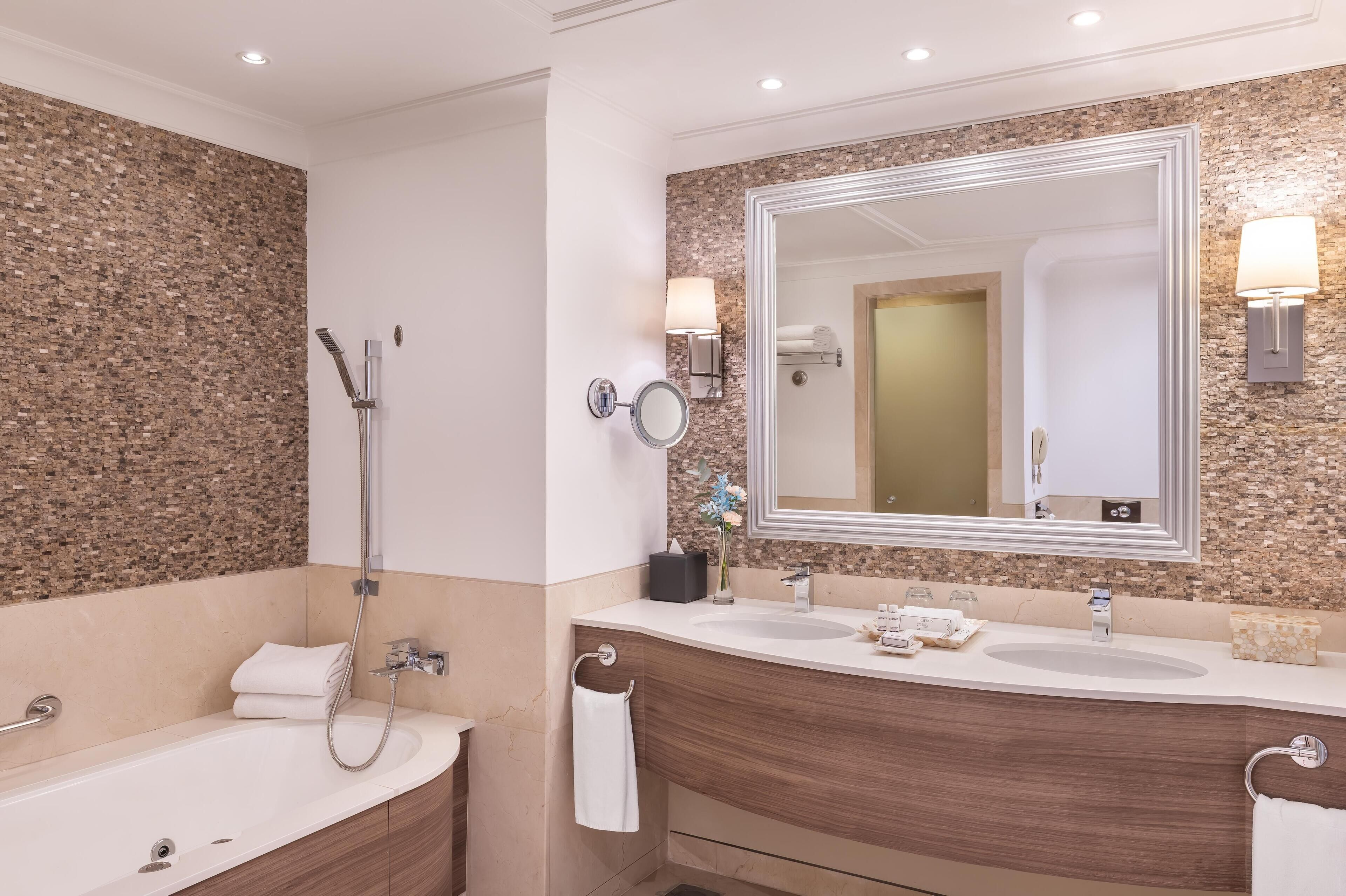 Un baño moderno con un espejo grande, dos lavamanos, una ducha y una bañera.