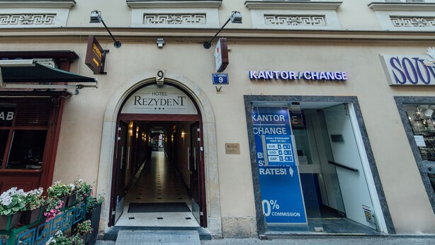 The entrance to Hotel Rezydent, featuring a prominent archway and a sign for Kantor Change currency exchange.