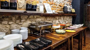 A buffet setup with various food items, stacked plates, and serving utensils.