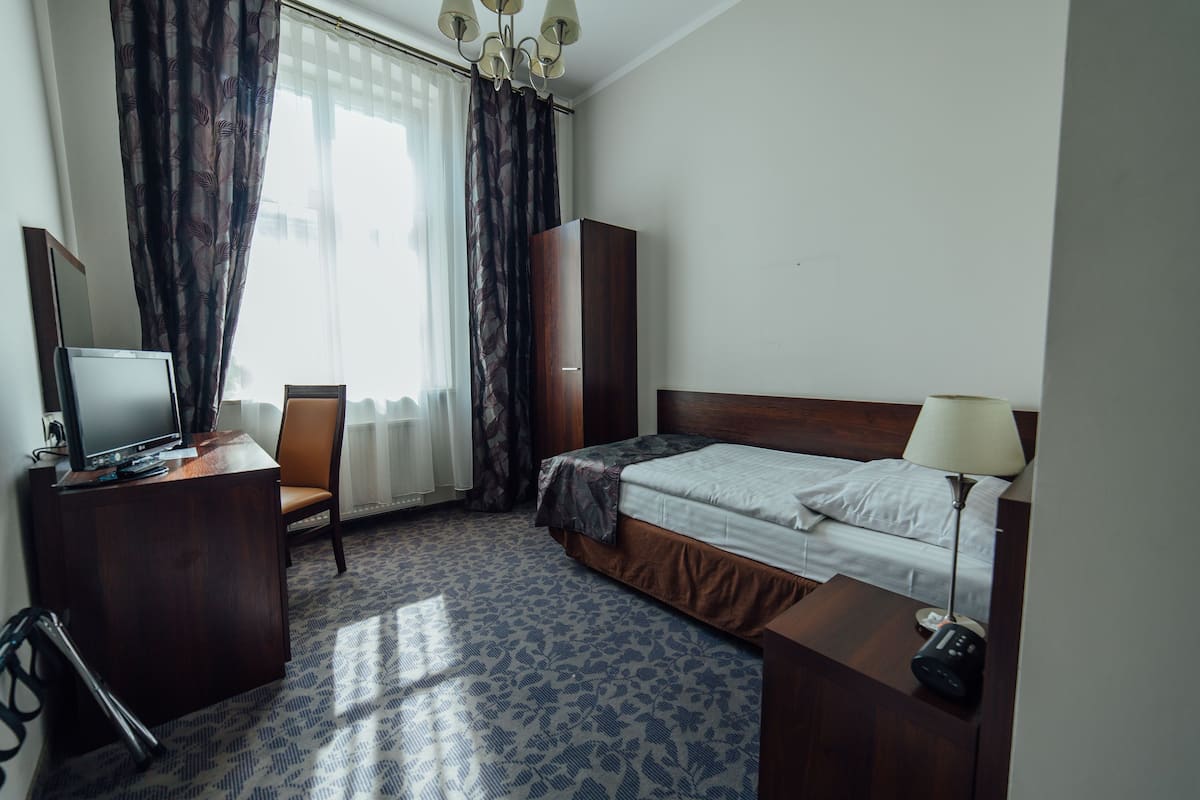 Habitación de hotel con cama, escritorio, computadora, silla, armario y lámpara.