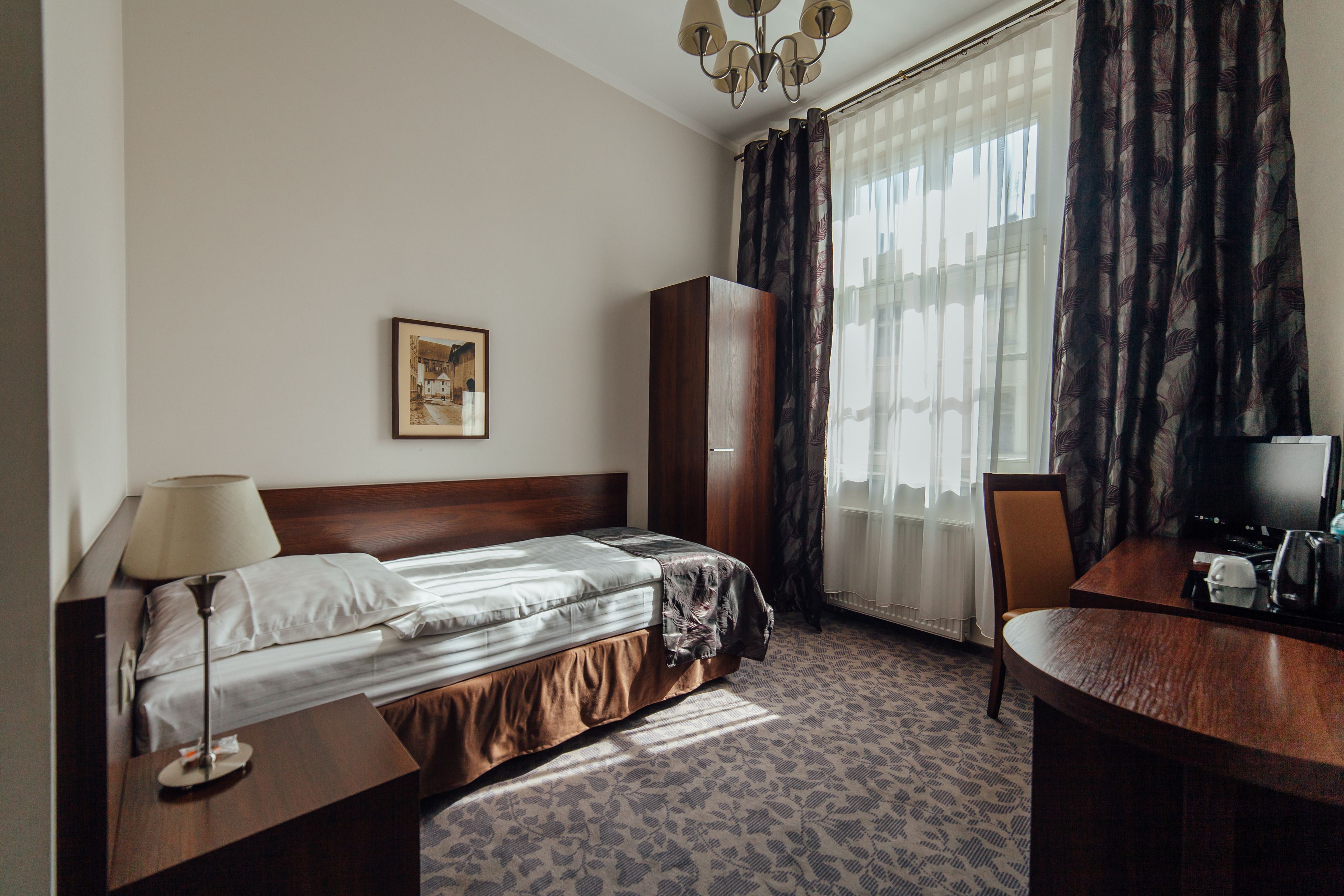Hotelkamer met een bed, een bureau, een stoel, een televisie en een raam met gordijnen.
