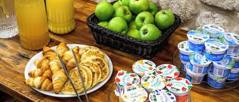 Un bufé de desayuno con cruasanes, manzanas y recipientes de yogur.