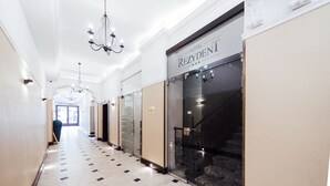 A hotel corridor with a chandelier, a glass door entrance, and a sign reading "HOTEL REZYDENIT".
