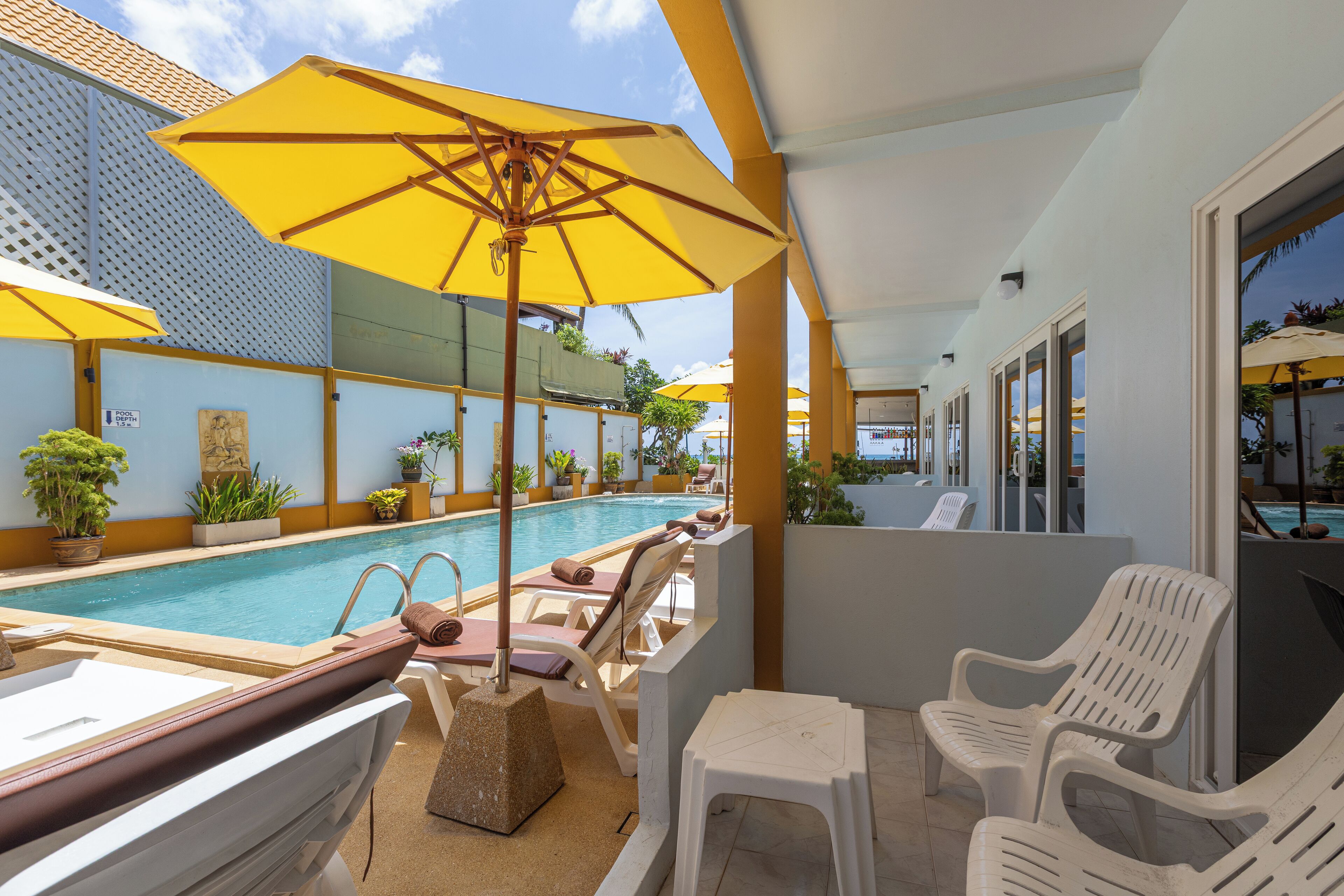 A poolside area with lounge chairs, umbrellas, and potted plants.