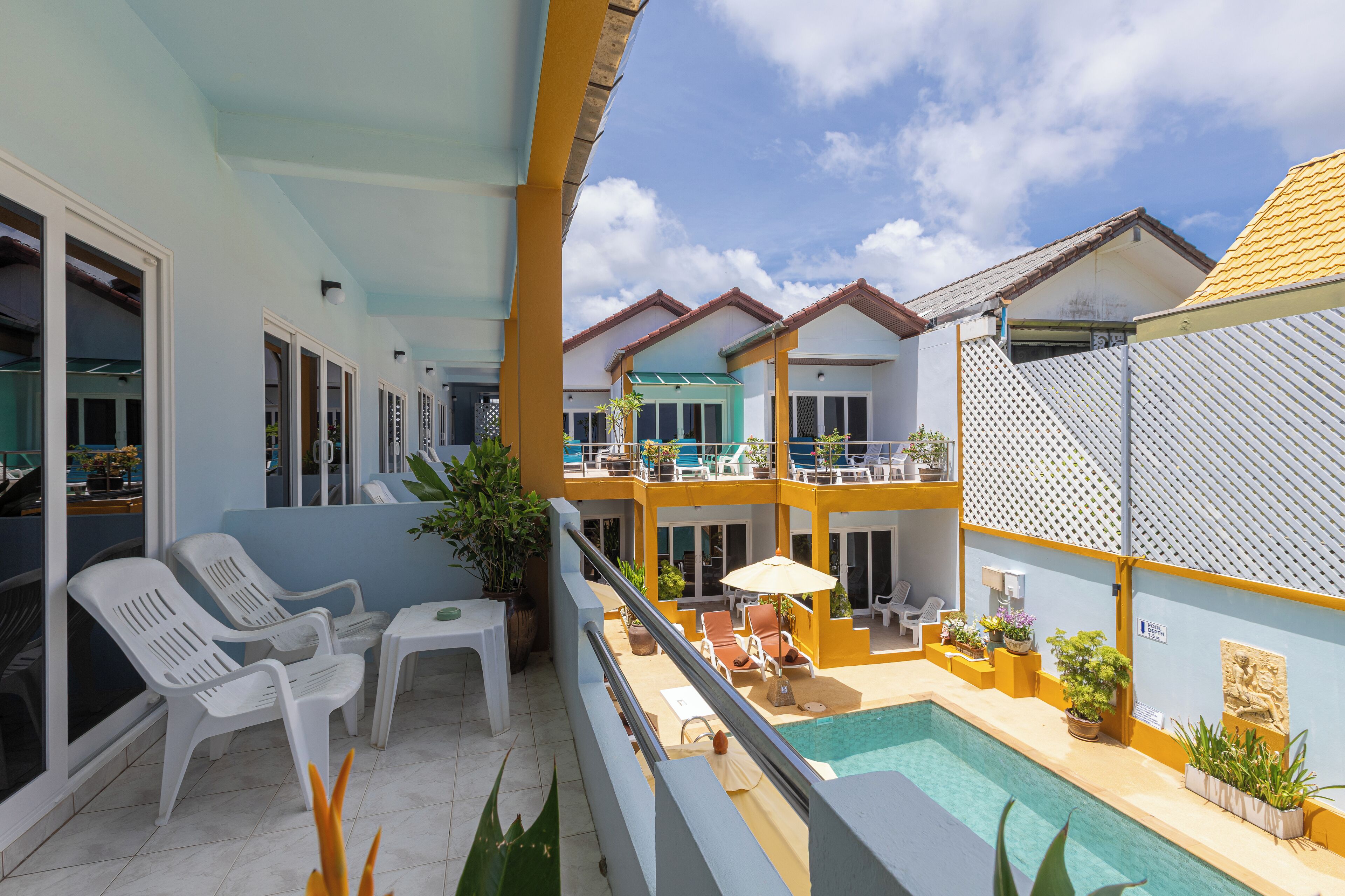 A hotel with a pool, white lounge chairs, and yellow accents.