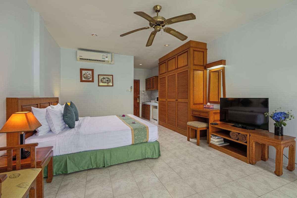 A hotel room with a bed, desk, television, and a ceiling fan.