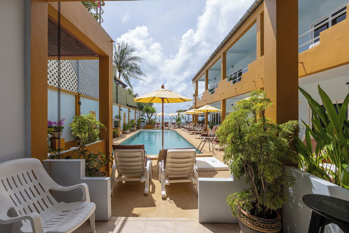 A poolside area with lounge chairs, umbrellas, and potted plants.