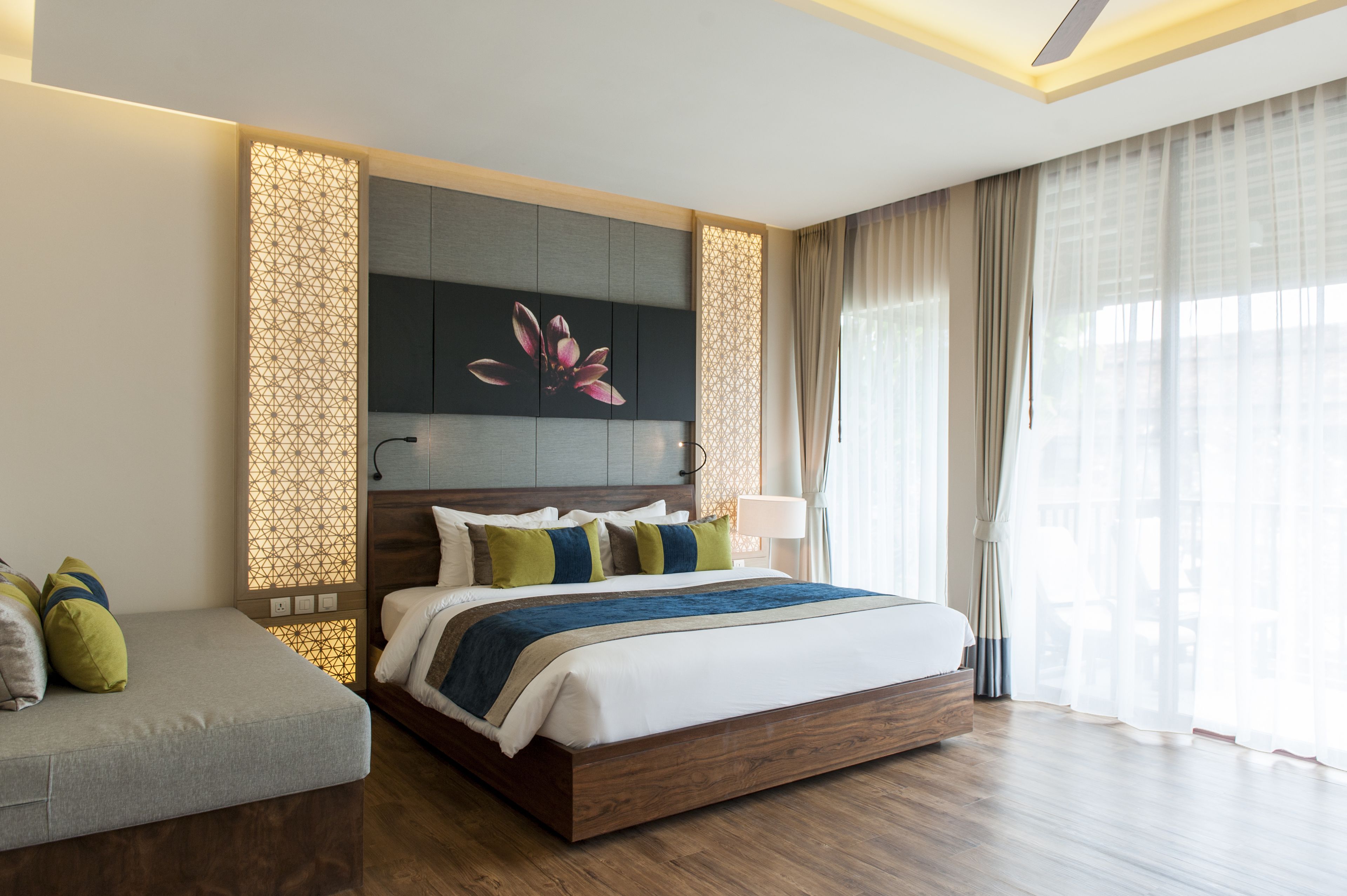 A modern hotel room with a large bed, a seating area, and a decorative wall panel.
