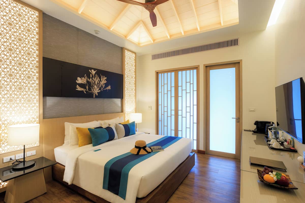 Una habitación de hotel moderna con una cama grande, un escritorio, un televisor y un frutero.